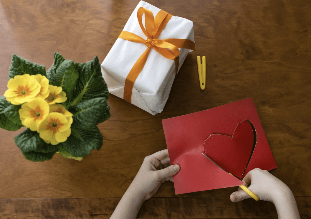 A person holding a red heart on top of a card.