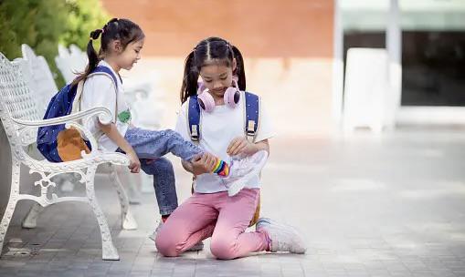 Two young girls are playing with a cell phone.