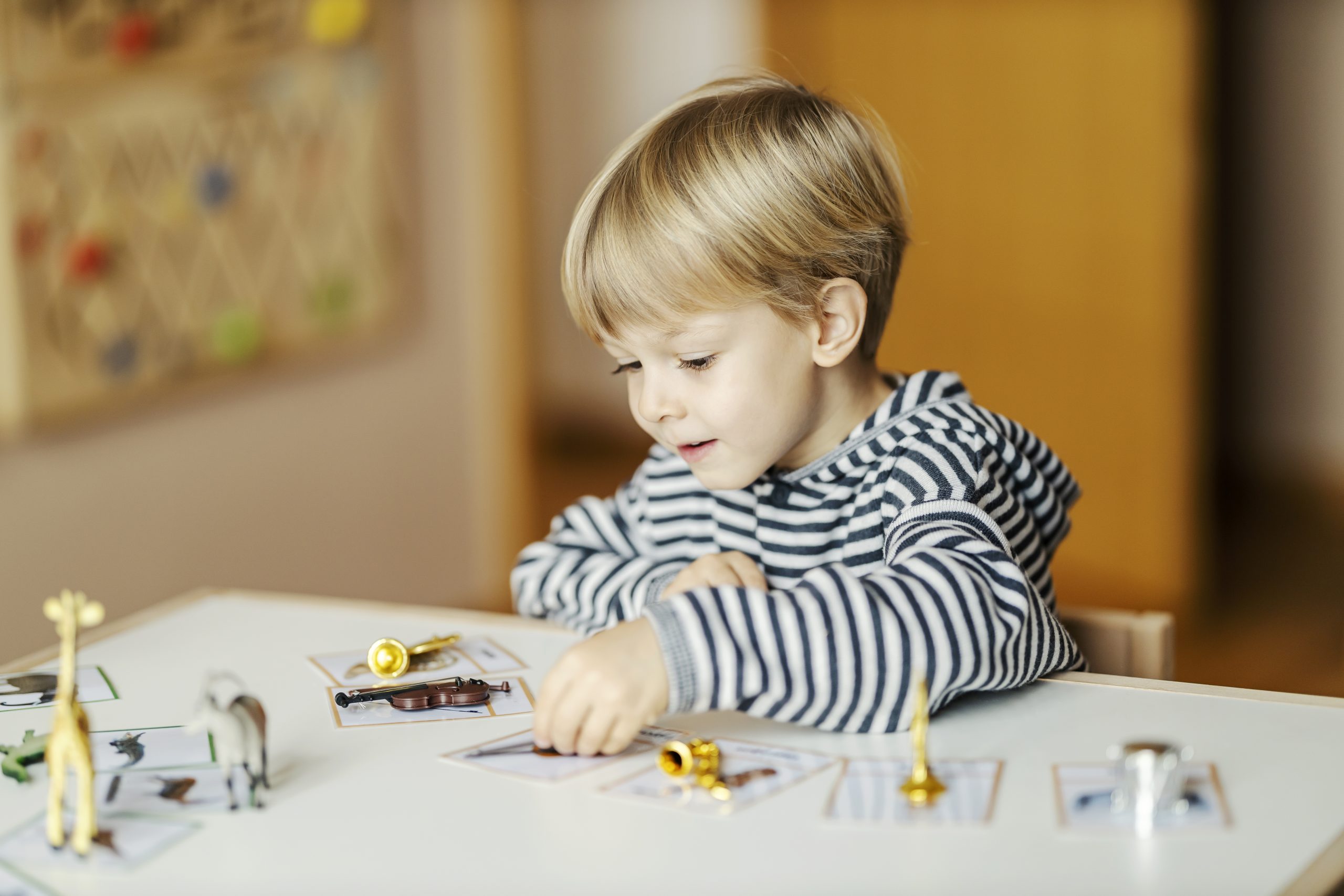 A young boy sitting at the table playing with toys.